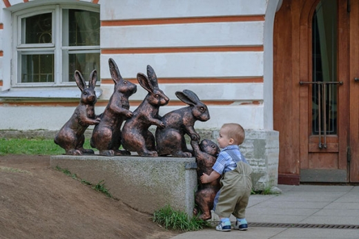‘넌 내가 도와줄게’ 토끼 조각품을 들어올리려는 아기.