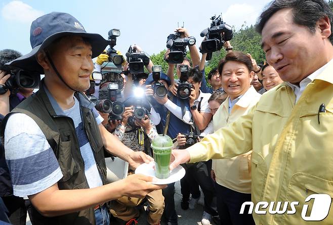 21일 오전 대구시민의 식수원인 낙동강 강정고령보 현장을 찾은 이낙연 국무총리가 환경관련 시민단체 회원으로부터 녹조가 담긴 컵을 전달받고 있다. 이자리에서 이 총리는 시민단체 회원에게 "아침에 녹차를 마시고 왔다"며'못마시겠다"고 웃으면서 유연하게 대응했다. 2017.6.21/뉴스1 © News1 이종현 기자