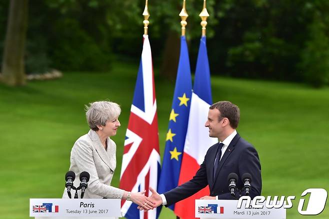 지난달 13일(현지시간) 프랑스 파리에서 정상회담을 가진 테레사 메이 영국 총리(왼쪽)와 에마뉘엘 마크롱 프랑스 대통령이 악수를 나누고 있다. © AFP=뉴스1