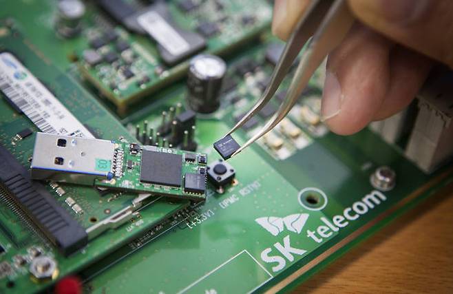 SK텔레콤 연구원이 손톱보다 작은 초소형 양자난수생성칩을 들어보이고 있다.