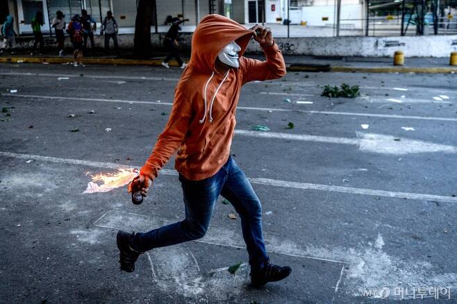 지난 26일(현지시간) 베네수엘라 수도 카라카스에서 니콜라스 마두로 대통령의 제헌의회 선거 강행에 반대하는 반정부 시위대 중 한명이 화염병을 던지고 있다. /AFPBBNews=뉴스1