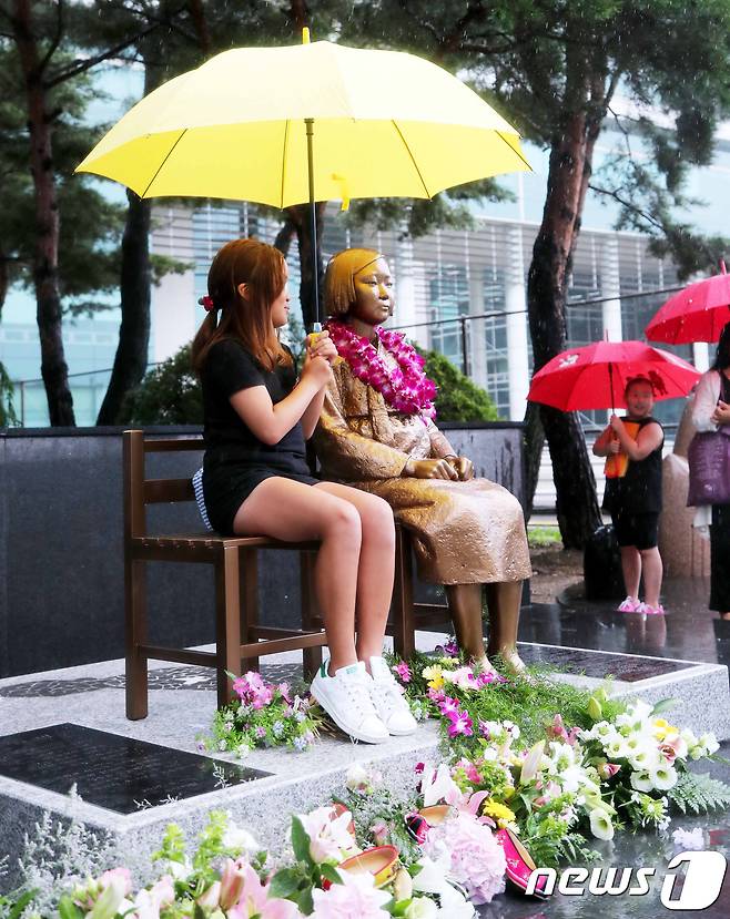평화의 소녀상에 한 소녀가 우산을 씌워주고 있다. (뉴스1/DB) © News1