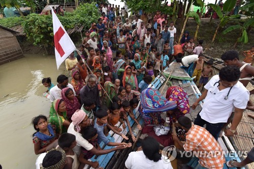 18일 인도 동북부 아삼 주 모리가온 지역에서 홍수 피해 지역 주민들이 의약품을 받고 있다.[AFP=연합뉴스 자료사진]