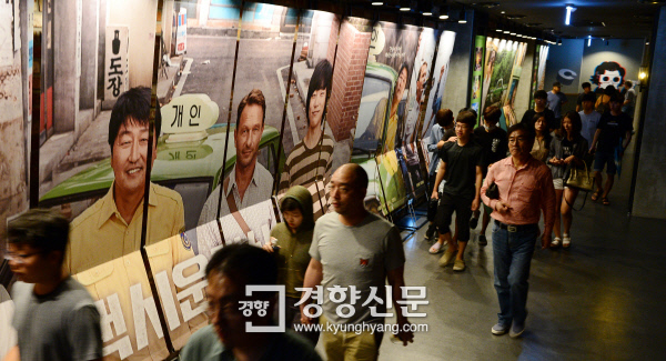 5·18 민주화운동을 다룬 영화 <택시운전사>의 관객수가 1000만명을 돌파한 20일 서울 시내의 한 복합영화관에서 관객들이 영화 포스터 옆을 지나고 있다.  정지윤 기자