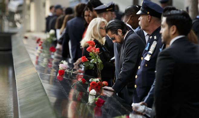 9ㆍ11테러 16주기를 맞은 11일(현지시간) 미국 뉴욕의 9ㆍ11 테러 추모공간 ‘그라운드 제로’에서 시민들이 테러 희생자의 이름이 새겨진 비석에 장미꽃을 꽂고 묵념을 하고 있다.[EPA=연합뉴스]