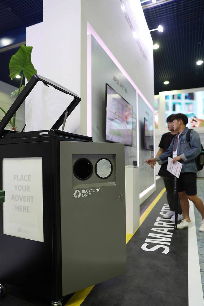 시민들이 LG 유플러스 부스에 설치된 스마트 쓰레기 수거관리 시스템을 살펴보고 있다. 이 제품은 상부에 태양열 집열판을 통해 충전이 가능하며, 센서를 통해 압축과 적재량을 파악할 수 있다. 우상조 기자