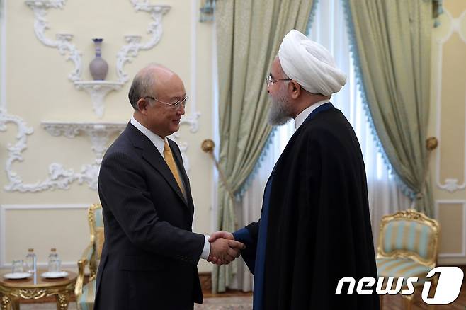 29일(현지시간) 아마노 유키야 IAEA 사무총장과 하산 로하니 이란 대통령이 악수를 나누고 있다. © AFP=뉴스1