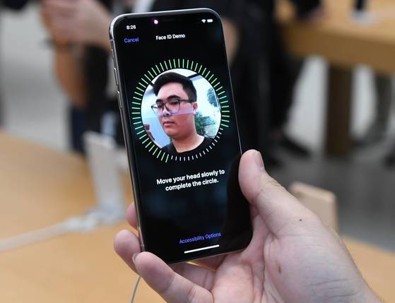 3일 싱가포르의 애플 매장에서 아이폰X를 구입한 한 고객이 얼굴인식 기능을 이용해 자신의 얼굴을 등록하고 있다. [AFP=연합뉴스]