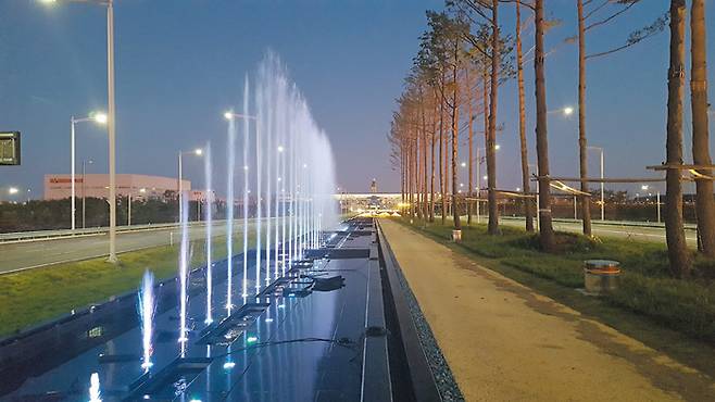 2터미널 앞 접근도로에 조성된 소나무길 옆에 분수가 작동하고 있다. 정면으로는 2터미널의 전체 모습이 보인다. 인천공항공사는 “지금은 터미널에서 소나무길까지 걸어가는 연결로가 없지만 향후 육교 등을 건설해 공항 이용객들이 잠시 조깅이나 산책을 할 수 있도록 할 것”이라고 말했다. / 인천공항공사 제공