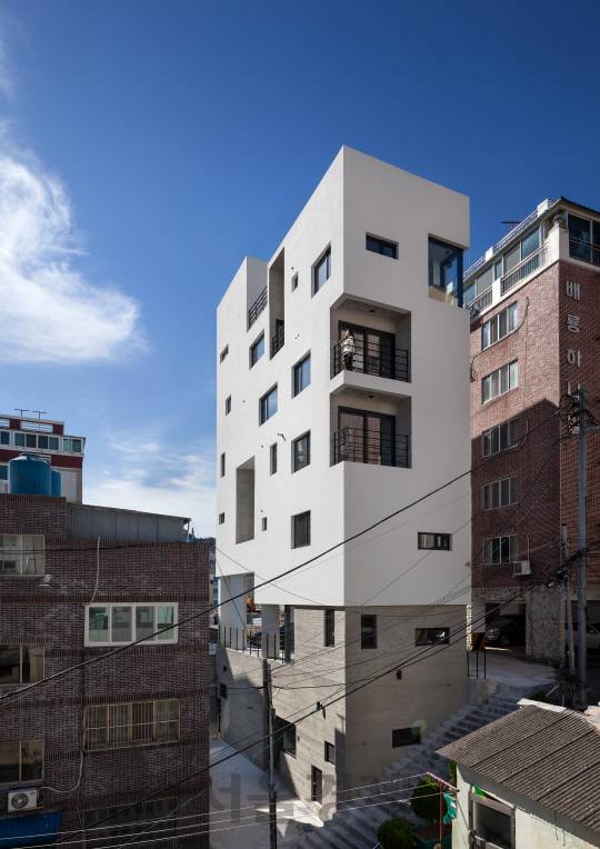 초량도시민박은 콘크리트 계단과 저층부의 송판 무늬 콘크리트가 조화를 이루며 상부의 백색 건물이 마치 공중에 떠 있는 듯한 느낌을 준다.