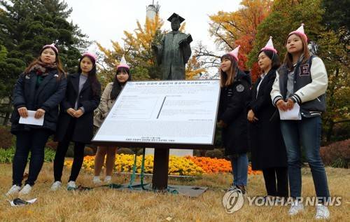 (서울=연합뉴스) 조현후 인턴기자 = 13일 오후 서울 서대문구 이화여자대학교 김활란 동상 앞에서 이화여대 친일청산 프로젝트 기획단 학생들이 김활란 친일행적 알림 팻말을 세우고 기념 촬영하고 있다.     who@yna.co.kr