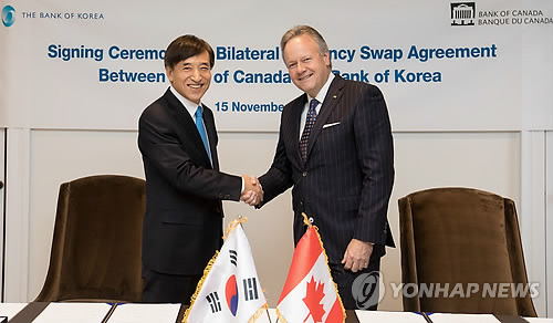 (서울=연합뉴스) 이주열 한국은행 총재(왼쪽)가 15일 오후(현지 시간) 캐나다 오타와에 위치한 캐나다중앙은행 본부에서 스티븐 폴로즈 캐나다중앙은행 총재와 양국간 통화스와프 협약서에 서명한 뒤 악수하고 있다. 2017.11.16 [캐나다중앙은행 제공=연합뉴스]      photo@yna.co.kr