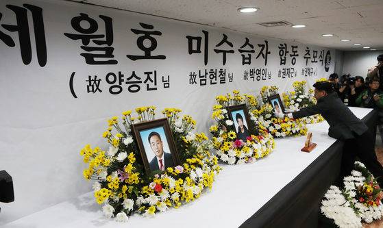 18일 오전 전남 목포신항에서 세월호 미수습자 5명의 추모식이 열려 장례 관계자가 제단에 영정을 놓고 있다. 세월호 미수습자 가족들은 유해 대신 유품을 관에 담아 장례절차에 들어갔다. [연합뉴스]