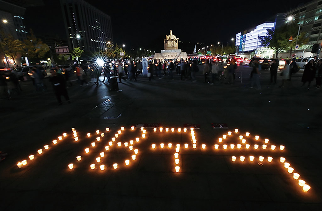 촛불집회 1주년(10월29일)을 앞둔 10월21일 서울 광화문광장에서 ‘이명박심판 범국민행동본부’ 관계자 등이 촛불집회를 열고 ‘MB구속’이라는 글씨를 만들고 있다. © 사진=연합뉴스
