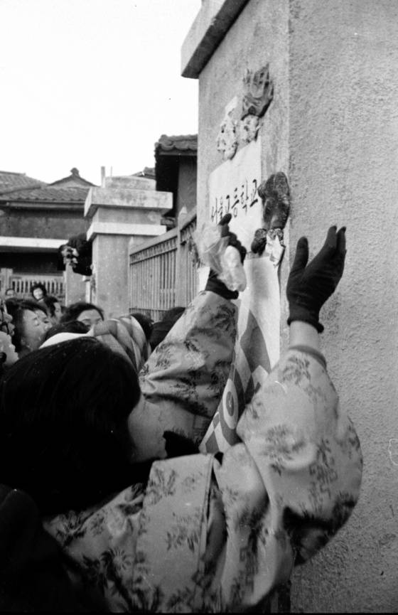 본고사가 열린 서울의 한 대학 시험장에서 학부모들이 교문에 엿을 붙이고 있다. 엿가락처럼 한번에 붙으라는 의미에서 엿과 떡 등을 교문에 붙이는 이들이 많았다. [중앙포토]