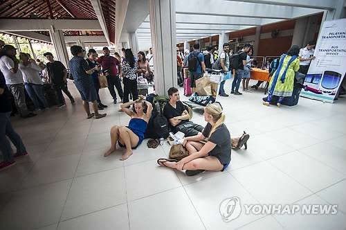 지난 28일 항공기 운항을 중단 중인 현지 덴파사르의 응우라라이 국제공항에서 여행객들이 바닥에 배낭 등을 내려 놓고 쉬고 있는 모습. [AFP = 연합뉴스 자료사진]