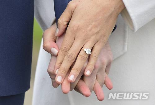【런던=AP/뉴시스】영국의 해리 왕자가 27일(현지시간) 약혼녀인 미국 영화배우 메건 마클과 함께 런던 켄징턴 궁의 정원에서 사진촬영을 하며 손을 잡고 있다. 마클이 낀 약혼 반지는 보츠나와에서 온 커다란 다이아몬드 하나와 해리 왕자의 어머니 다이애나 왕세자비의 유품인 작은 다이아몬드 두 개가 박힌 모양이다. 두 사람은 2018년 봄 결혼할 예정이다. 2017.11.28