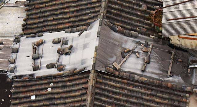 비가 새는 기와 지붕의 일부를 비닐로 씌우는 땜질 식 보수가 인사동에선 흔하다.