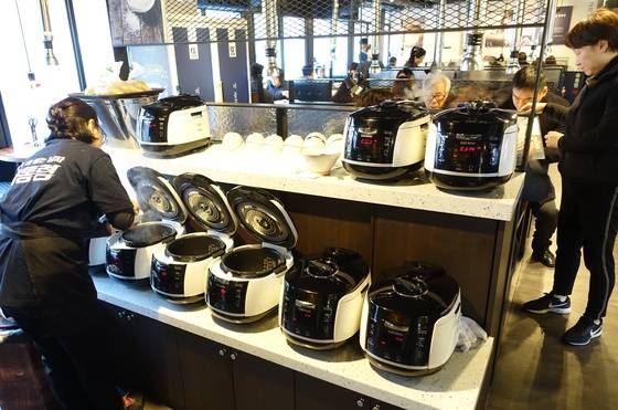 교대점에 들어서면 9개의 밥솥이 먼저 손님을 반긴다. 한창 바쁜 점심시간에 직원이 밥을 푸고 있다. 교대점에는 정미기(맨 왼쪽 밥솥 옆)를 설치하고 현미를 매일 즉석 도정해 밥을 짓는다. 정미기 위의 비닐봉지에 든 노란 가루는 현미를 도정할 때 나오는 속쌀겨다. 원하면 토장찌개에 풀어주고 나눠주기도 한다.