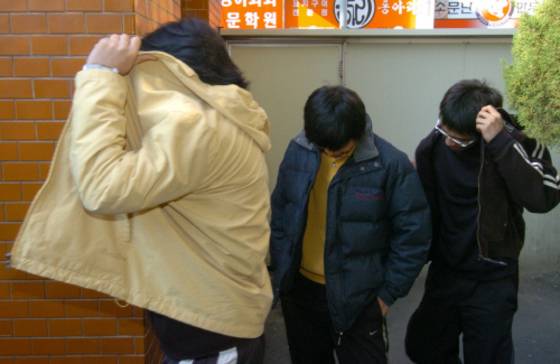 2004년 휴대전화로 조직적 부정행위를 저지른 학생들이 21일 조사를 받기위해 광주 동부서로 들어서고 있다.[중앙포토]