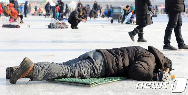 일 강원 홍천군 홍천강변에서 제6회 홍천강 인삼송어 축제가 개막했다. 한 관광객이 얼름구멍을 들여다 보고 있다. 이번 축제는 오는 21일까지 계속되며 주요 프로그램은 얼음낚시, 가족텐트낚시, 인삼송어 맨손잡기 등이다. 2018.1.5/뉴스1 © News1 하중천 기자