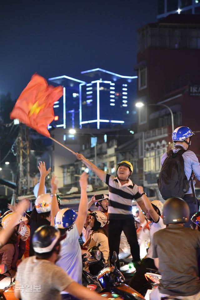 한 시민이 자신의 오토바이에 올라 서 베트남 국기를 흔들고 있다.