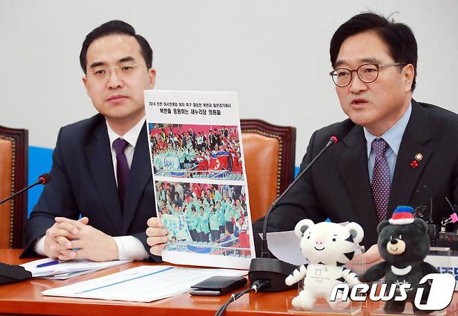 우원식 더불어민주당 원내대표가 23일 오전 서울 여의도 국회 본청에서 열린 원내대책회의에서 지난 2014년 인천아시안게임 여자축구 결승전에서 북한을 응원하는 새누리당 의원들의 언론기사를 들어 보이고 있다. 2018.1.23/뉴스1 © News1 이동원 기자