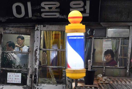 이 씨는 한 번 머리를 손질하는데 기본 5∼6 종류의 가위를 번갈아 사용한다. “이발은 가위와 빗으로 만들어내는 작품이야!  요즘은 공장에서 찍어내는 것처럼 머리 모양이 너무 비스하다.”며 아쉬움을 내 비친다. 이씨 부인인 이욕연(사진 우측)씨가 영업이 끝나기를 기다리고 있다.