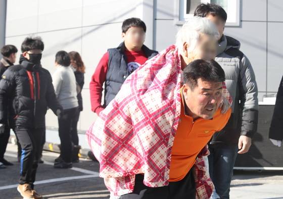 26일 오전 경남 밀양시 가곡동 세종병원에서 불이나자 일반 시민이 환자를 업고 긴급히 대피시키고 있다.[연합뉴스]