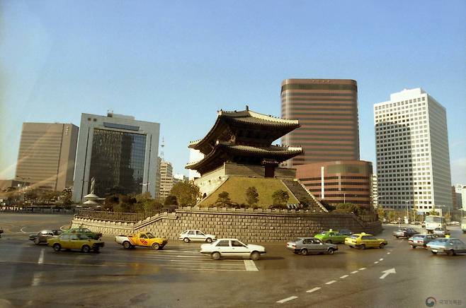 남대문 시장 쪽에서 바라본 숭례문. 1987년 모습으로 고층빌딩과 지금과 사뭇 다른 당시 자동차가 눈에 띈다.[사진 국가기록원]