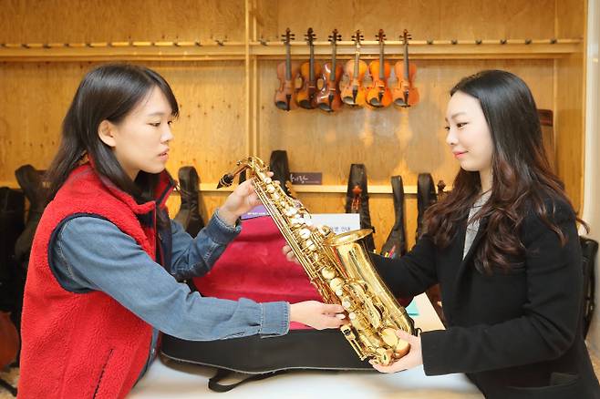 12일 경기 성남아트센터 2층 야외광장에 있는 악기도서관 ‘악기랑’ 직원(오른쪽)이 색소폰을 대여해 줄 한 여성에게 악기 관리 방법을 설명하고 있다.  성남문화재단 제공