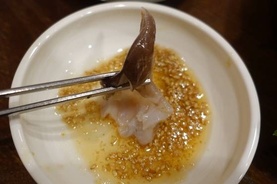 새조개 살을 기름소금에 찍는 모습.