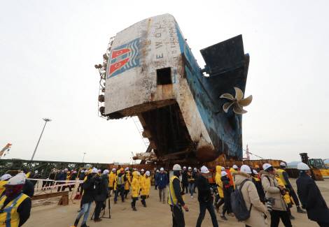 작업자들과 유가족들이 지난달 21일 오전 전남 목포신항에서 세월호를 모듈트랜스포터(MT)에 실어 부두 수평 방향으로 재배치한 뒤 선체의 상태를 살폈다. 세월호는 이날 목포신항에 거치된 지 316일 만에 부두와 수평 방향으로 자리를 옮겼다. 세월호는 오는 5월 31일 선체 직립 작업을 통해 세워질 예정이다.[사진=연합뉴스]