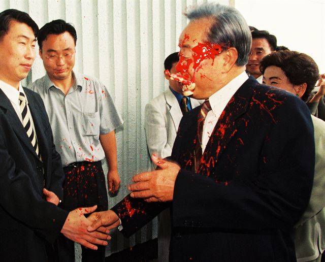 [제36회 대상 - 김영삼 전 대통령 페인트 달걀 봉변] 외국 순방길에 나선 김영삼 전 대통령이 김포공항 제2청사에서 환송객과 악수하던 중 붉은 페인트로 채워진 달걀 세례를 받았다. 범인 박의정씨가 달걀을 던진 순간 김 전 대통령은 물론 손명순 여사와 주변 사람들도 순식간에 일어난 사건을 인식하지 못한 채 웃고 있는 얼굴로 포착되었다. 1999.6.3 한국일보 고영권 기자