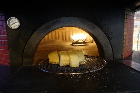 식전빵을 테이블에 내가기 앞서 피자화덕에서 데우고 있다.