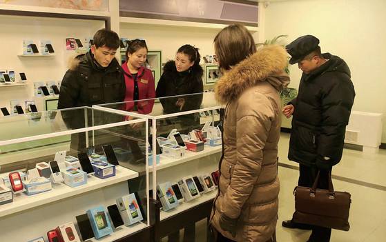평양의 한 휴대전화 매장에 진열된 스마트폰을 둘러보는 시민들. 이용에 제약이 있는 자체 생산제품 외에 중국서 들여온 중고 기기도 암암리에 거래된다. [사진출처·북한 대외선전매체 웹사이트]