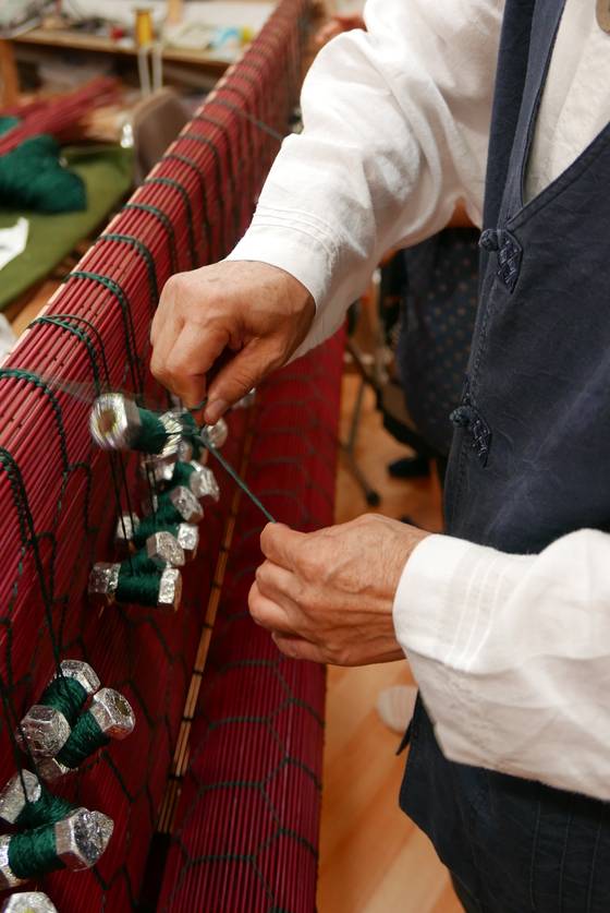 대나무를 가늘게 쪼개 붉게 염색한 후 한올한올 엮고 있는 장인의 모습. [사진 아름지기]