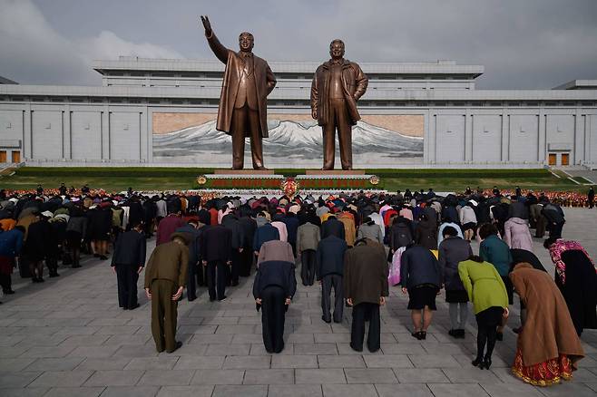 15일 북한 평양 만수대 언덕에 이른 아침부터 모인 사람들이 김일성과 김정일의 동상을 향해 묵념하고 있다. [AFP=연합뉴스]