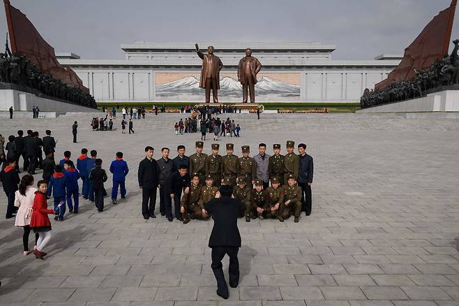 북한 주민들과 군인들이 15일(현지시간) 북한 평양 만수대 언덕의 김일성과 김정일의 동상을 배경으로 기념사진을 찍고 있다. [AFP=연합뉴스]