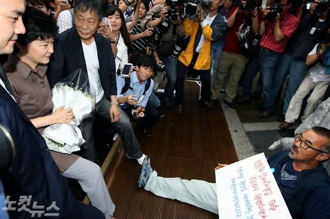 지난 2012년 8월 28일, 당시 박근혜 새누리당 대선 후보가 서울 종로구 청계천 6가 전태일 다리로 이동해 전태일 열사 동상 앞에서 추모하려 하자 한 쌍용자동차 노조원이 드러누워 이를 거부하고 있다. 박 후보는 당초 창신동에 있는 전태일재단을 찾아 전태일 열사를 추모할 예정이었으나 "진정성이 없다"는 유가족 측의 반대로 무산됐다. (사진=자료사진/노컷뉴스)