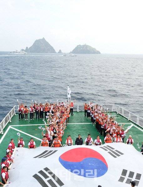 ‘제71주년 광복절 기념 독도 순례행사’ 참가자들이 15일 오전 5001함 헬기갑판에서 독도를 배경으로 숫자 ‘71’자로 대열을 맞춰 기념촬영을 하고 있다. (사진=전상희 기자)
