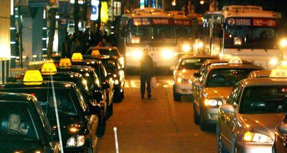 네온사인 대신 택시 표시등 행렬이 인적이 끊어지기 시작한 깊은 밤 도심의 거리를 밝히고 있다. 심야 지하철 운행과 함께 최근 심각한 경기침체로 인해 모범·일반택시 모두가 손님이 없어 어려움을 겪고 있다. 서울 명동 입구에 빈 택시들이 줄지어 서 손님을 기다리고 있다.