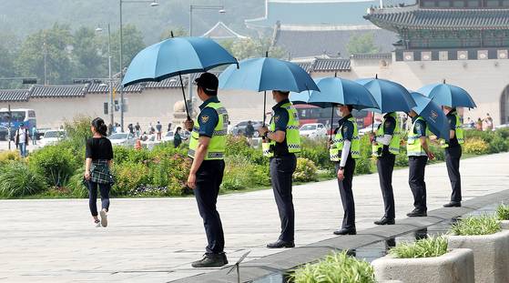 28일 광화문광장에서 근무 중인 경찰들이 햇볕을 가리기 위해 우산을 쓰고 있다. [뉴스1]