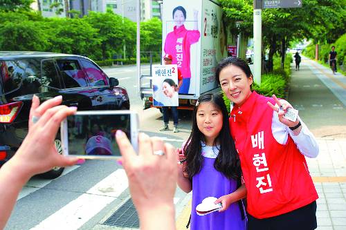 붉은색 조끼를 입은 배현진 자유한국당 후보가 4일 송파구 잠실주공 5단지 아파트 앞에서 어린이와 함께 사진을 찍으면서 2번 표시를 하고 있다. 배현진 후보 캠프 제공