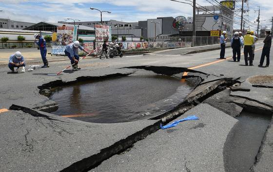 근로자들이 오사카 타카쓰키 지역에서 강진으로 도로에 생긴 웅덩이를 살피고 있다. [지지통신=연합뉴스]