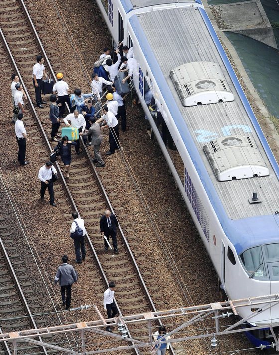 오사카 지역 강진으로 타카스키에서 열차 운행이 중단되자 승객들이 걸어서 이동하고 있다.[교도=연합뉴스]