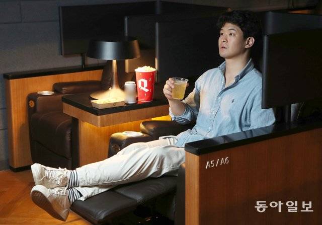 서울 신도림 씨네Q의 혼영족 특별관을 찾아 맥주와 팝콘을 먹으며 영화 관람을 즐기는 관객. 혼영족 특별관은 한 회차에 30여 명만 이용 가능한 소규모로, 리클라이너(전 자동 각도 조절) 의자와 독립적 공간 확보를 위한 개인 파티션이 설치돼 있다. 양회성 기자 yohan@donga.com