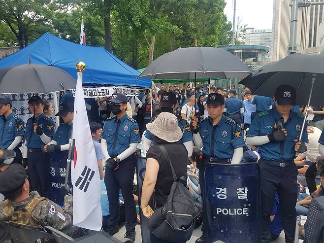 4일 오후 서울 대한문 앞에 해고된 쌍용차 사망 조합원의 분향소가 차려진 가운데, 태극기혁명국민운동본부 관계자들이 "광화문으로 가라"며 항의하자 경찰이 양측을 갈라놓은 모습이다. 홍지유 기자