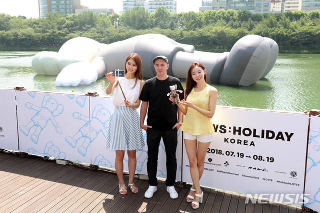 【서울=뉴시스】김선웅 기자 = 19일 오후 서울 송파구 석촌호수에서 팝 아티스트 '카우스(KAWS)'와 모델들이 공공 미술 프로젝트 '카우스:홀리데이 코리아(KAWS:HOLIDAY KOREA)'를 배경으로 포즈를 취하고 있다. ‘카우스:홀리데이(KAWS:HOLIDAY)’는 길이 28M(세로), 25M(가로), 5M(높이)의 독창적인 캐릭터를 활용해 ‘일상으로부터 탈출해 모든 것을 잊고 세상을 바라보며 휴식을 취하는 모습’을 표현한다. 전시는 다음달 19일까지 관람할 수 있다. 2018.07.19. mangusta@newsis.com