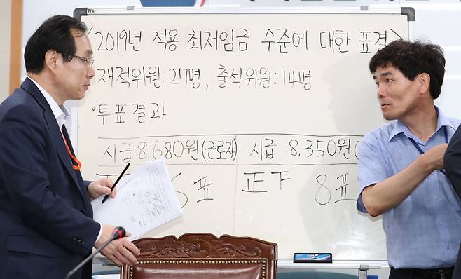 ▲ 지난 7월14일 새벽 정부세종청사 고용노동부에서 열린 최저임금위원회 전원회의에서 내년도 최저임금이 확정돼 류장수 위원장(왼쪽)이 브리핑을 마친 뒤 고용노동부 직원과 이야기를 하고 있다. ⓒ 연합뉴스